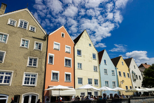 View of colorful historic buildings in the town center with white umbrellas and people enjoying a sunny day in Landsberg am Lech, Bavaria, Germany.