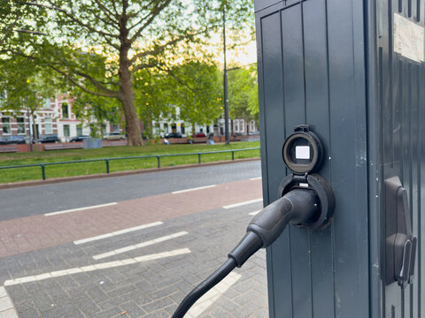 Electric vehicle charging cable closeup at streetside station near park in Rotterdam Netherlands