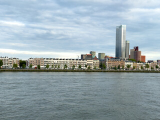 Obraz premium Rotterdam Centrum skyline across river with waterfront homes and modern towers under storm clouds, Netherlands