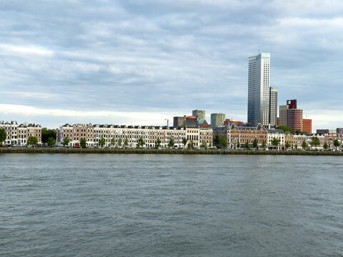 Rotterdam Centrum skyline across river with waterfront homes and modern towers under storm clouds, Netherlands