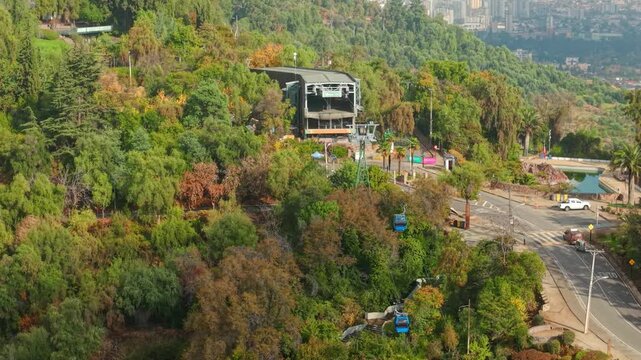 Telephoto aerial orbit of the Santiago de Chile cable car, suspended gondolas in a natural setting with dense trees