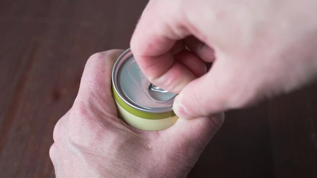 Opening beer can on wooden table close up