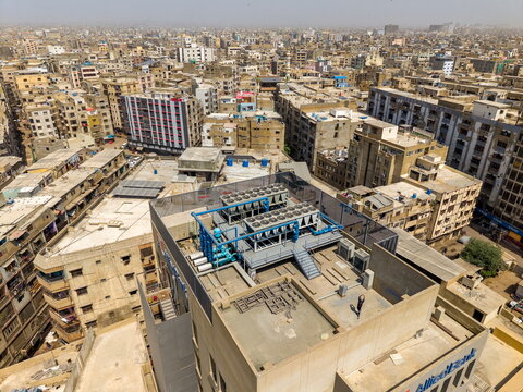 Aerial view of HVAC cooling units on a rooftop overlooking the dense urban landscape of I.I. Chundrigar Road in Karachi, Sindh, Pakistan.