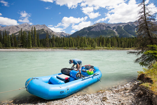 Man prepares inflatable raft for river trip