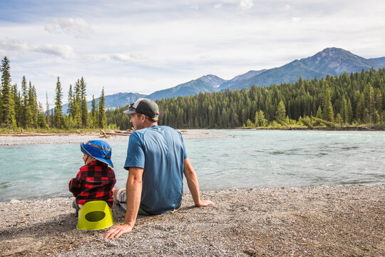 Father and son potty training by a mountain river