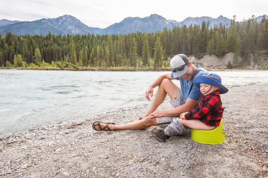 Dad helps toddler potty train by mountain river