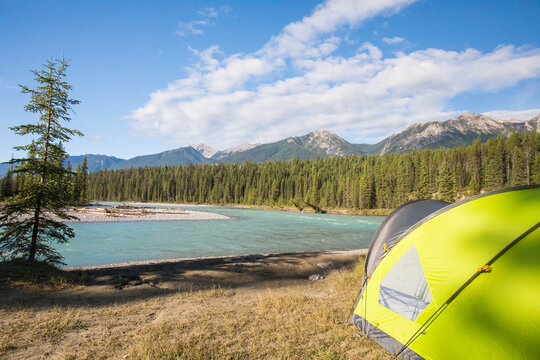 Tent pitched by a turquoise river in the mountains