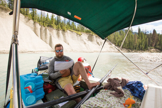 Bearded man reviews a map on a river raft trip