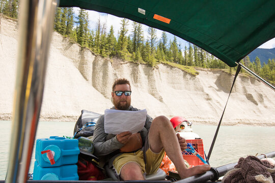 Bearded man reads a map on a river raft adventure