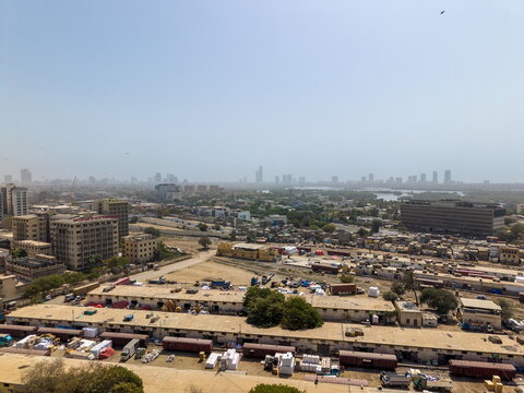Aerial view of the urban landscape featuring industrial buildings, railway tracks with freight cars, and a distant city skyline in Karachi, Sindh, Pakistan.