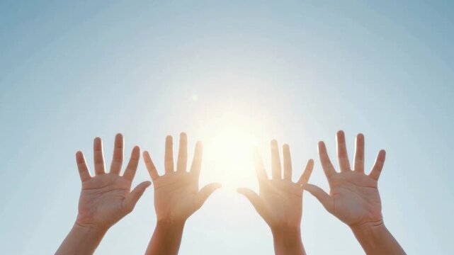 Human hands raised toward bright sun with clear blue sky background symbolizing hope freedom unity and positive energy on a sunny day