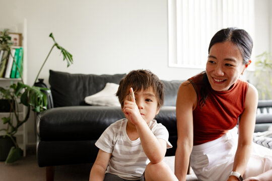 Toddler boy sitting on the floor beside mum with plaster on finger