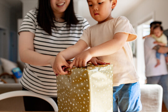 Young boy helping mum wrapping a present