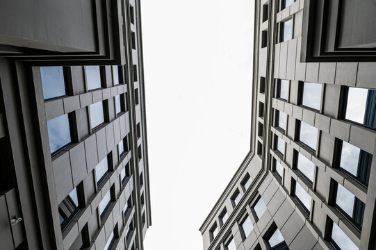 View upwards between tall buildings, featuring reflective windows