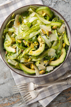 Shaved Asparagus Salad with avocado, arugula, cheese and pistachios closeup in the plate on the table. Vertical top view from above