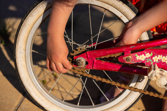 Hands fixing chain on pink bicycle