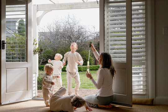 Young boys playing in the doorway with mum blowing bubbles
