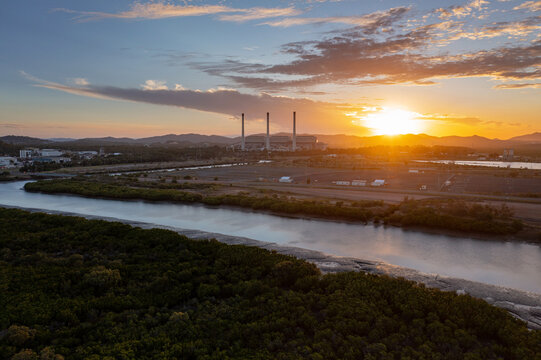 Industrial smokestacks with sunset over river landscape