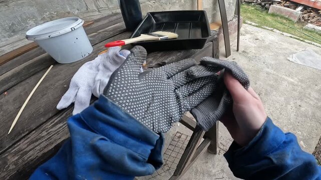 The process of replacing protective cotton gloves. Painting work. A woman takes off one work glove and puts on another. Hand protection during physical labor. First person view