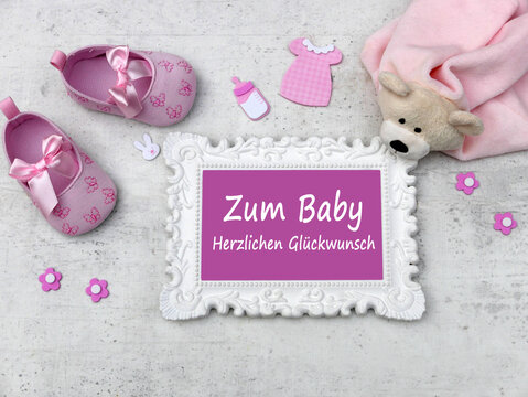 Gl&uuml;ckwunschkarte zur Geburt eines M&auml;dchens mit rosa Babyschuhen, Teddyb&auml;r und  Bilderrahmen mit dem Text Zum Baby herzlichen Gl&uuml;ckwunsch.
