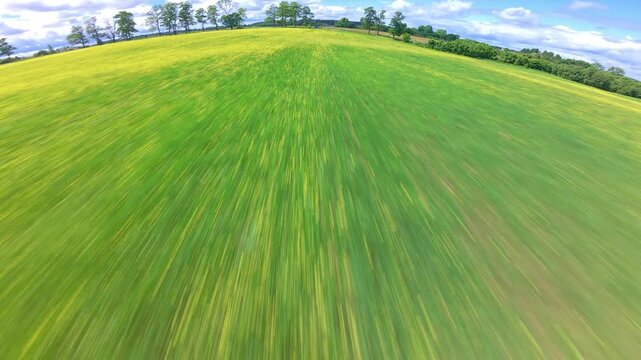 Horizontal drone footage performing dynamic aerial maneuvers above a green field. Cinematic flight showcasing rural landscape, open terrain and fast drone movement.

