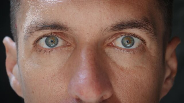 Close up of male eyes expressing light shock and fear. Open gaze and tense facial muscles show alarm danger awareness and instinctive response used in psychology thriller and stress concepts.