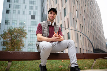Obraz premium Young man relaxing on urban bench with headphones