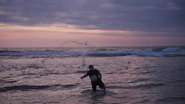 Fisherman casting a net into the ocean at sunset