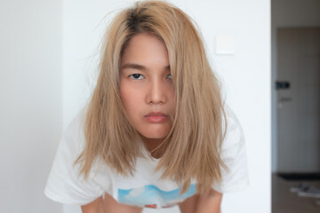 Naklejka premium Funny Serious Young Woman with Intense Expression Looking at Camera Indoors, Moody Lifestyle Portrait with Blonde Hair, Confidence, Attitude and Natural Emotion Concept