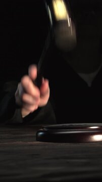 Judge's hand striking gavel on black background close-up, final decision, announcement of the verdict, vertical video