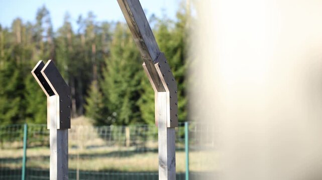 Close up of two timber posts with layered metal brackets and even fasteners. Subtle lateral pan reveals repeating posts, shallow depth of field, warm light.