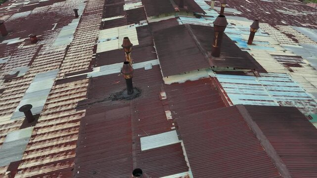 A close-up aerial view showing the factory&rsquo;s rusted corrugated metal roof with several rusted smokestacks.