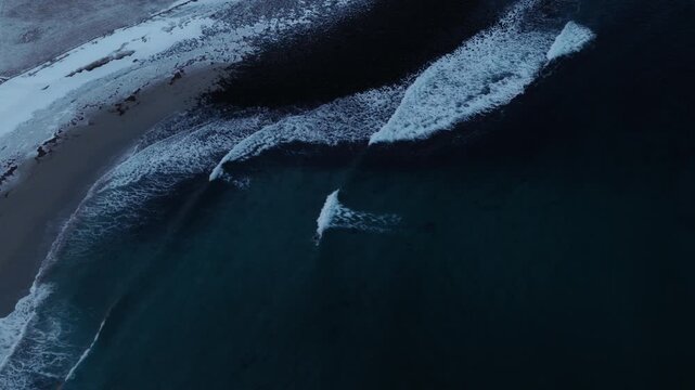 Tilt down to waves crashing, aerial of Arctic beach and deep blue coastal waters, drone establishing background