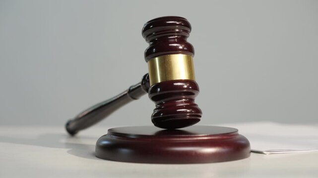 Ceremonial wooden gavel of judge or auctioneer swinging on stand on table on light background