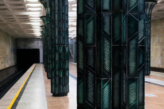 Ornate green ceramic columns inside Gafur Gulom metro station in Tashkent. Empty platform with geometric tile patterns and Soviet-era architectural grandeur, ideal for travel and urban design content.