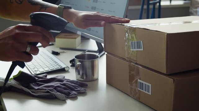 Cropped shot of warehouse worker typing on keyboard and scanning barcode on cardboard box with scanner. Clip is ideal for logistics, e-commerce fulfillment, and supply chain management videos