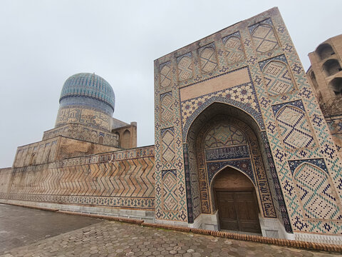 Bibi Khanum Mosque facade with turquoise dome and ornate tilework in Samarkand on an overcast day. Ideal for travel publications, heritage content, and architectural features.
