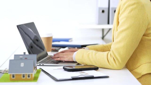 Business woman real estate agent, doing paperwork with laptop for investment strategy, review or planning.