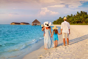 Rear view of a family on vacations looking at a tropical paradise beach in the Maldives islands during sunset time © moofushi