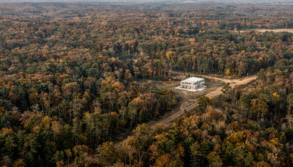 Naklejka premium Aerial View of Winding Dirt Road Through Dense Forest in Autumn Landscape