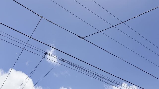 Tangyled power lines and white clouds in the blue sky. Honolulu, Oahu, Hawaii