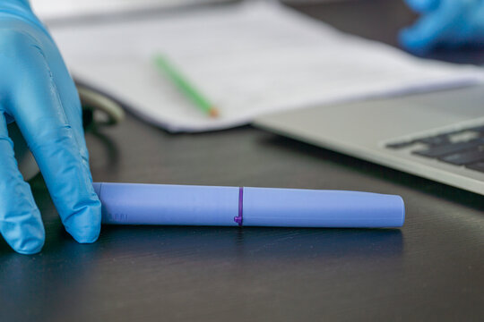 ozempic pen hand holding medical injection weight loss drug office desk background, doctor reviewing patient documents with diabetes medication, clinical treatment process