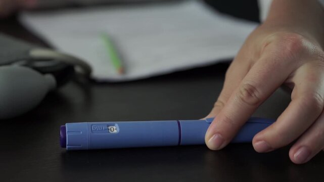 ozempic pen hand holding medical injection weight loss drug office desk background, doctor reviewing patient documents with diabetes medication, clinical treatment process