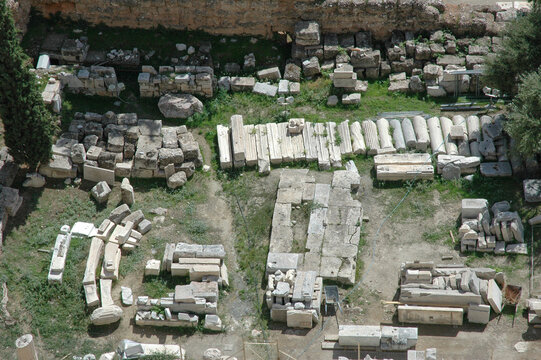 Birdseye view of scattered ancient marble columns and stone blocks organized for restoration at the historical Sanctuary of Asklepios in Athens Greece.
