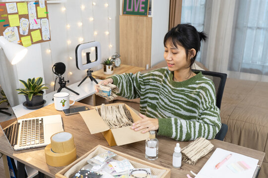 Young small business Seller online packing products into a shipping box for online orders at home studio