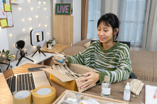 Young small business Seller online packing products into a shipping box for online orders at home studio