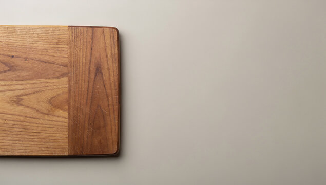 Top view of wooden cutting board edge on matte beige surface background