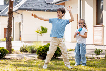 Obraz premium Happy children playing with soap bubbles in garden