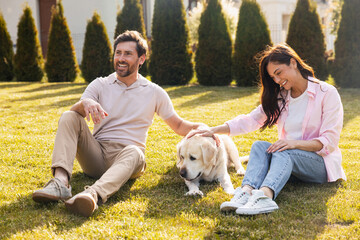 Fototapeta premium Happy couple relaxing with golden retriever in backyard