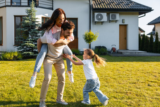 Happy family enjoying piggyback ride in backyard